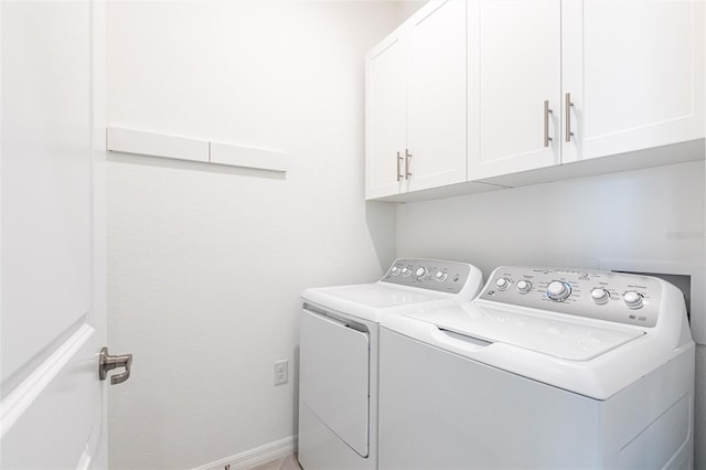 clothes washing area featuring cabinets and washer and clothes dryer