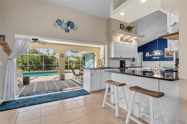 kitchen featuring lofted ceiling, white cabinetry, decorative backsplash, sink, and a breakfast bar area