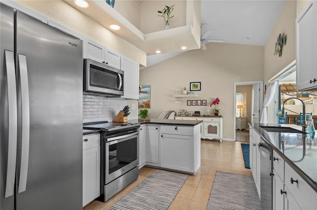 kitchen featuring kitchen peninsula, sink, white cabinets, decorative backsplash, and stainless steel appliances