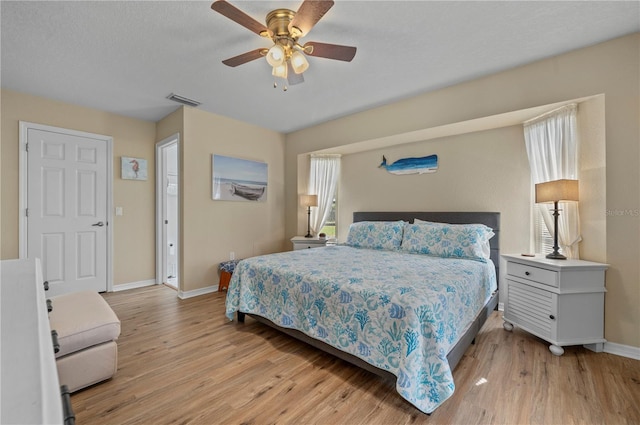 bedroom featuring ceiling fan, light hardwood / wood-style floors, and multiple windows