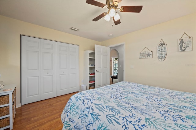 bedroom with ceiling fan, wood-type flooring, and a closet