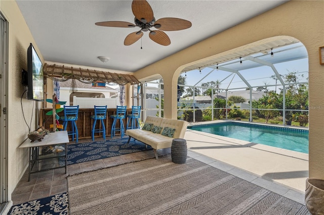 view of pool featuring a patio area, a bar, glass enclosure, and ceiling fan