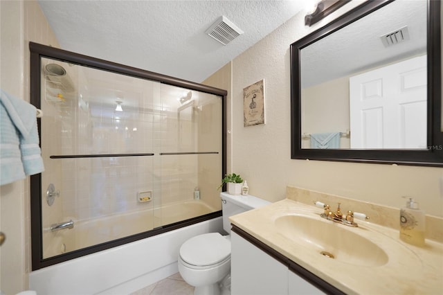 full bathroom with shower / bath combination with glass door, tile patterned flooring, vanity, a textured ceiling, and toilet