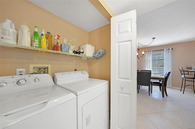 clothes washing area with separate washer and dryer, light tile patterned floors, a textured ceiling, and a chandelier