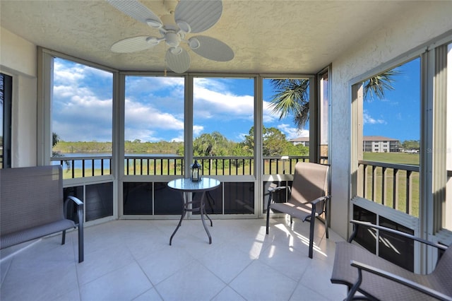 sunroom / solarium with a water view and ceiling fan