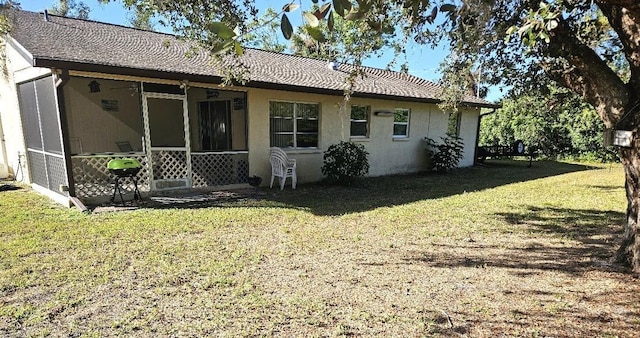 back of property with a sunroom and a yard