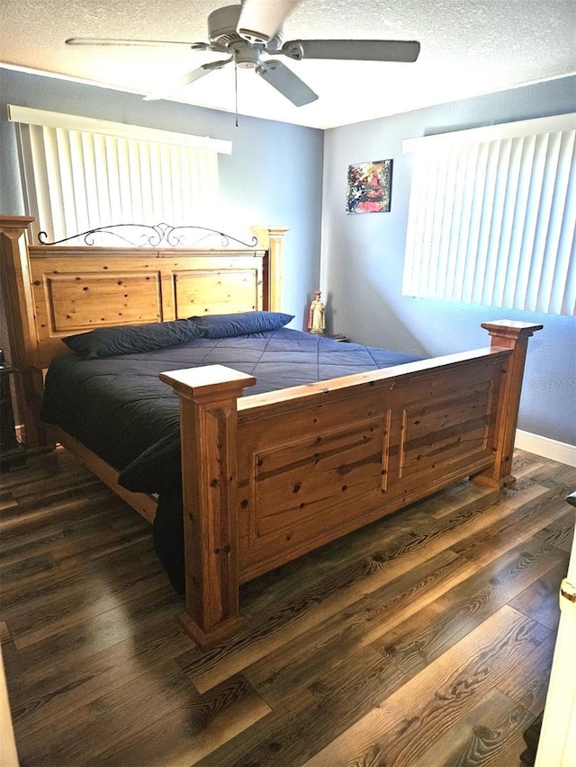 bedroom with dark wood-style floors, multiple windows, a textured ceiling, and baseboards