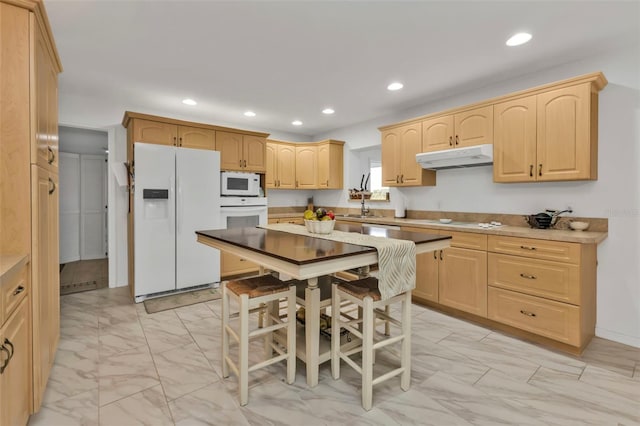 kitchen with light brown cabinetry, sink, and white appliances