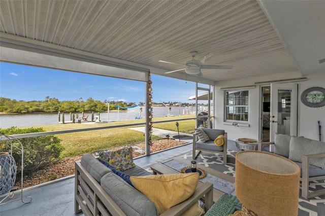 sunroom with ceiling fan and a water view