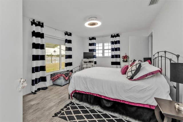 bedroom with multiple windows and light hardwood / wood-style flooring