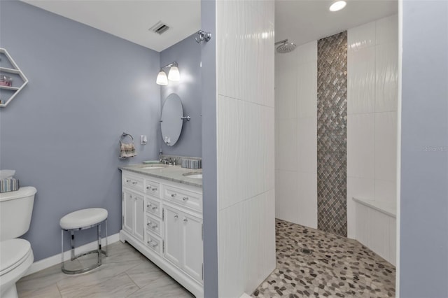 bathroom with vanity, a tile shower, and toilet