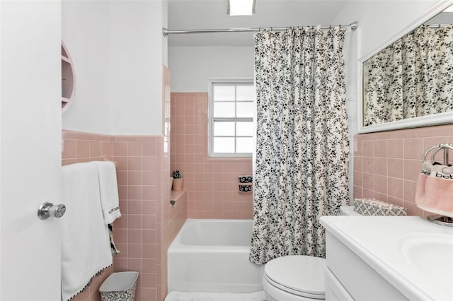 full bathroom with vanity, tile walls, shower / bath combo with shower curtain, and toilet