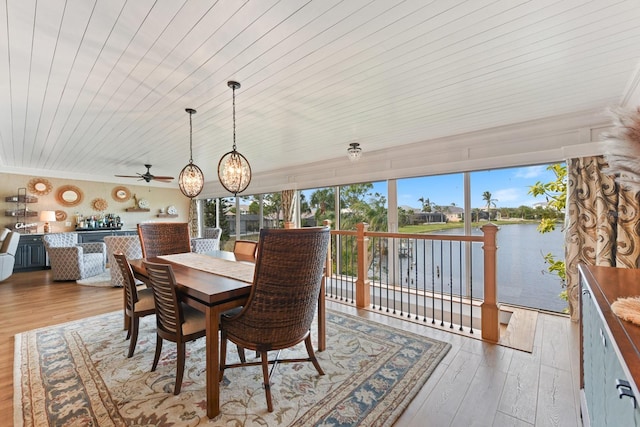 dining area with crown molding, light hardwood / wood-style floors, wooden ceiling, and a water view