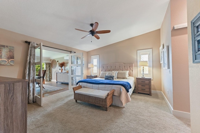 bedroom featuring multiple windows, vaulted ceiling, light colored carpet, and ceiling fan