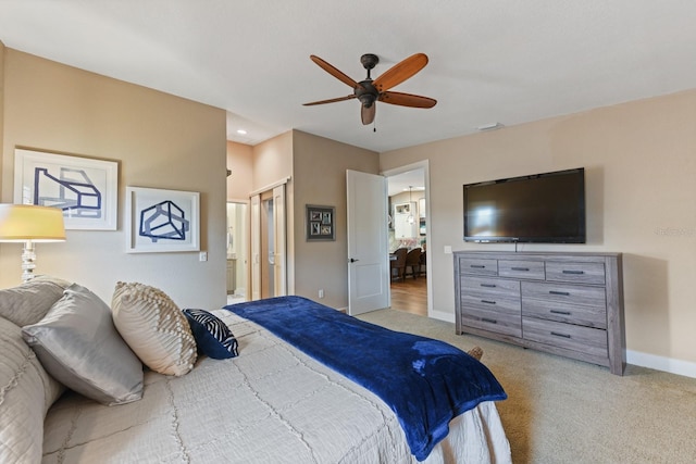 bedroom featuring connected bathroom, light colored carpet, and ceiling fan