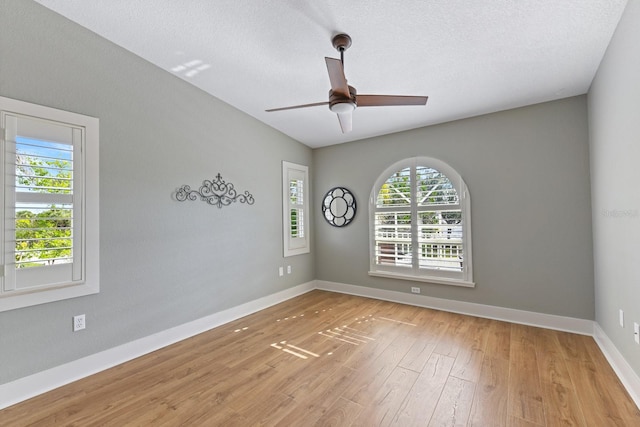 unfurnished room featuring ceiling fan, a textured ceiling, light hardwood / wood-style flooring, and a wealth of natural light