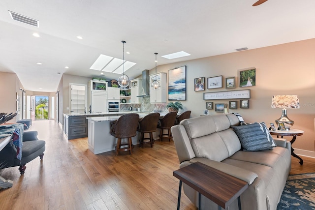 living room with lofted ceiling with skylight and light hardwood / wood-style floors