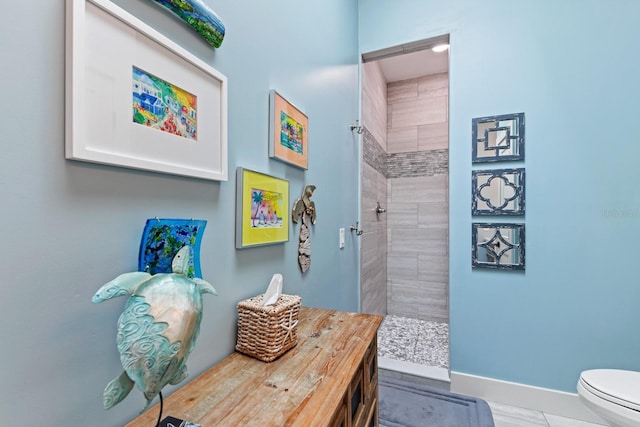 bathroom with a tile shower and toilet