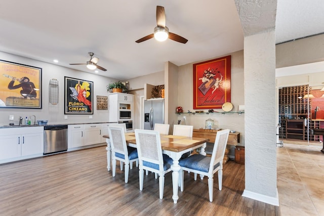 dining space featuring ornate columns, wet bar, ceiling fan, and light hardwood / wood-style flooring