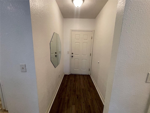 corridor with dark hardwood / wood-style flooring and a textured ceiling