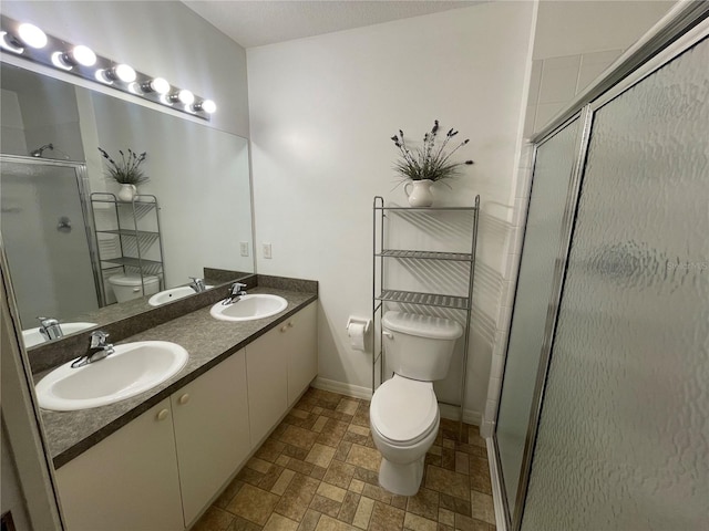 bathroom with a shower with shower door, toilet, and vanity