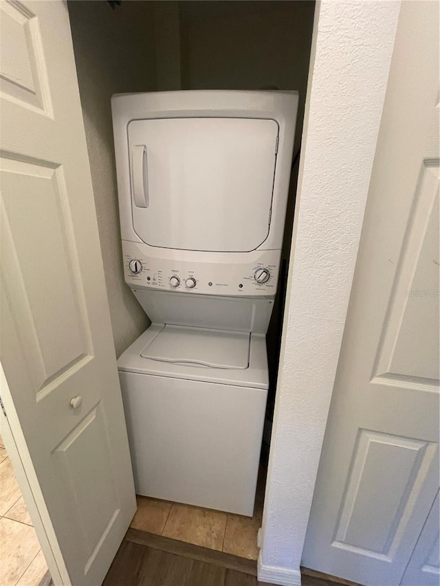 laundry room featuring stacked washer and dryer and tile patterned flooring