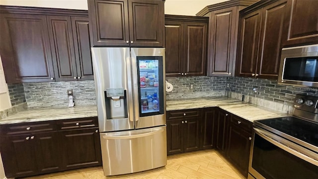 kitchen with backsplash, light stone countertops, light hardwood / wood-style floors, and appliances with stainless steel finishes