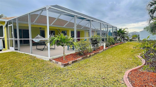 rear view of property featuring a lawn, a patio, and glass enclosure