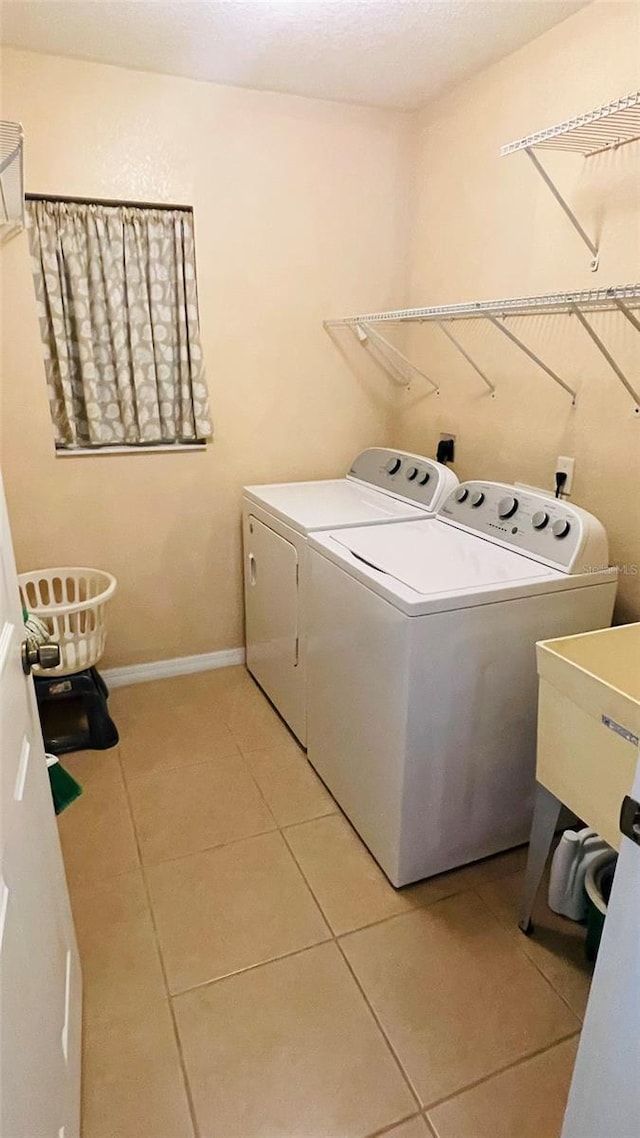 washroom with sink, washer and clothes dryer, and light tile patterned flooring