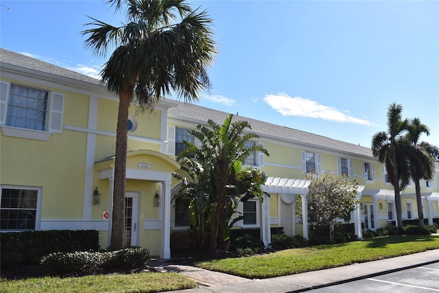 view of front facade featuring a pergola and a front lawn