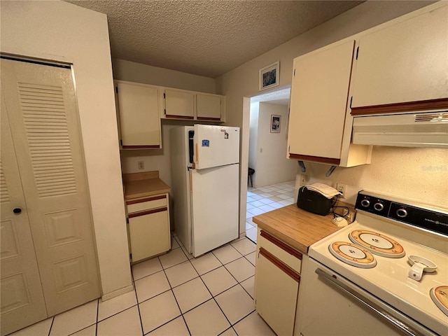 kitchen featuring white appliances, a textured ceiling, and light tile patterned flooring