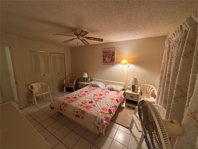 bedroom featuring light tile patterned flooring, ceiling fan, a closet, and a textured ceiling