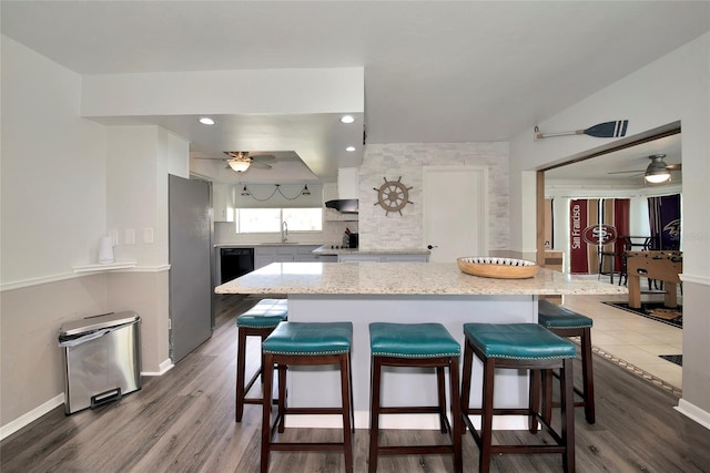 kitchen with white cabinetry, sink, light stone counters, dark hardwood / wood-style floors, and stainless steel fridge