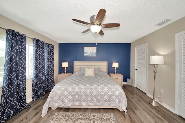 bedroom with ceiling fan, a textured ceiling, and hardwood / wood-style flooring