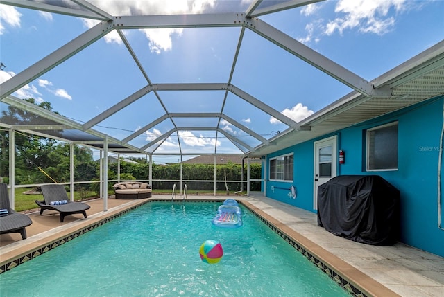 view of pool featuring glass enclosure, a patio area, and a grill