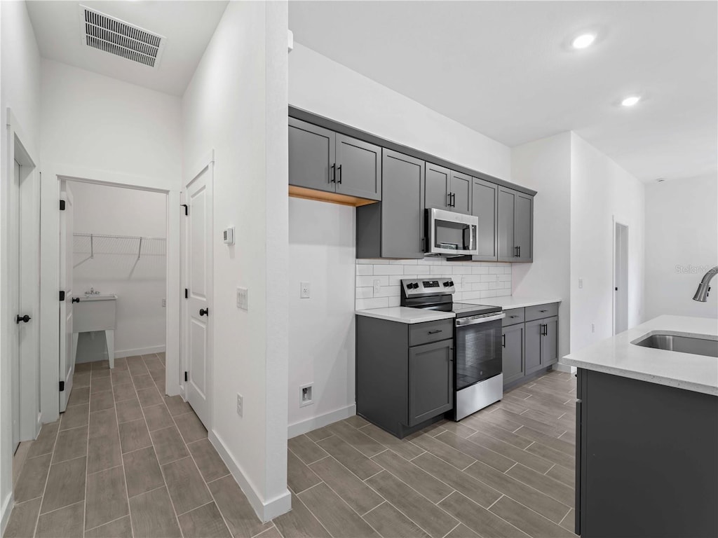 kitchen featuring decorative backsplash, sink, gray cabinets, and stainless steel appliances