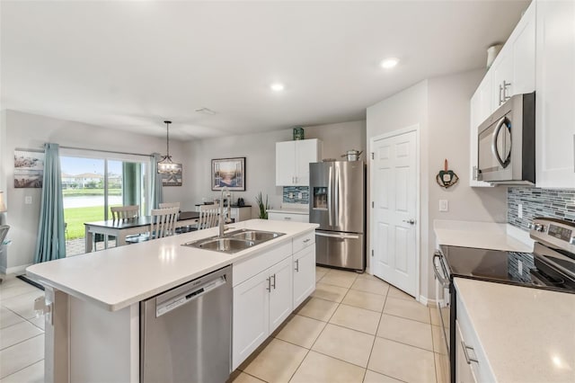 kitchen featuring pendant lighting, appliances with stainless steel finishes, sink, white cabinetry, and an island with sink