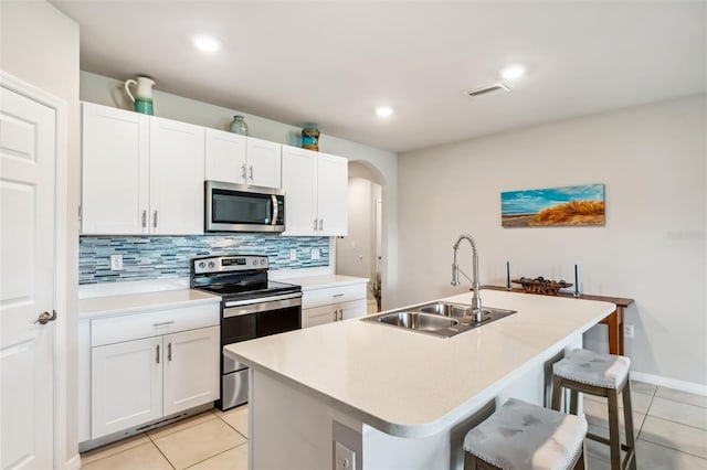 kitchen with appliances with stainless steel finishes, sink, white cabinets, a breakfast bar, and an island with sink