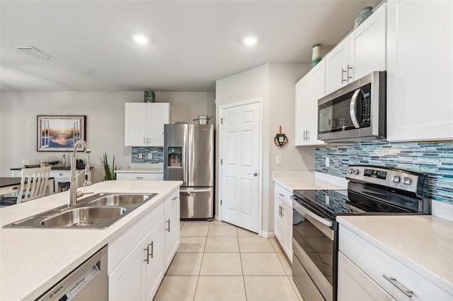 kitchen with light tile patterned flooring, white cabinets, decorative backsplash, and appliances with stainless steel finishes