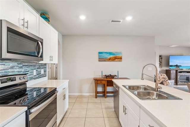 kitchen featuring sink, backsplash, white cabinetry, light tile patterned flooring, and stainless steel appliances