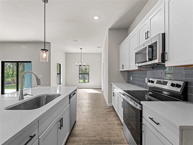 kitchen featuring sink, backsplash, white cabinetry, light stone countertops, and stainless steel appliances