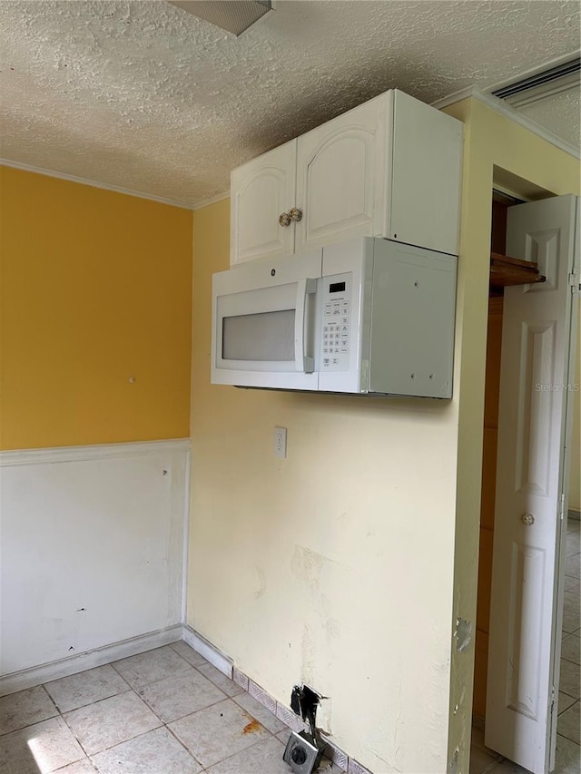 laundry area with light tile patterned floors and a textured ceiling