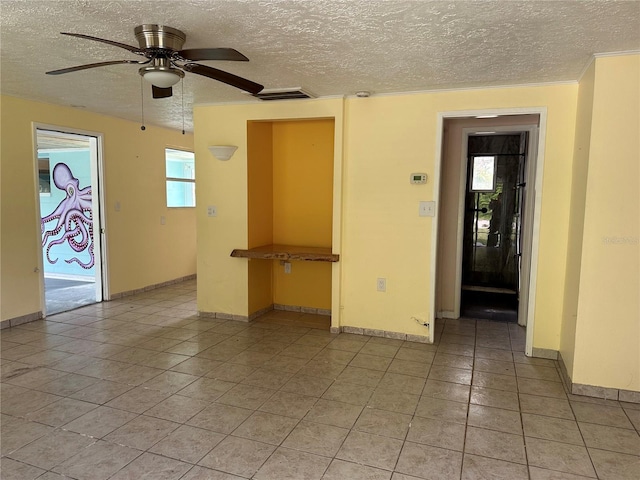 tiled empty room with a textured ceiling and ceiling fan