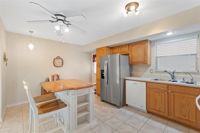 kitchen featuring hanging light fixtures, white dishwasher, sink, stainless steel fridge with ice dispenser, and light tile patterned flooring