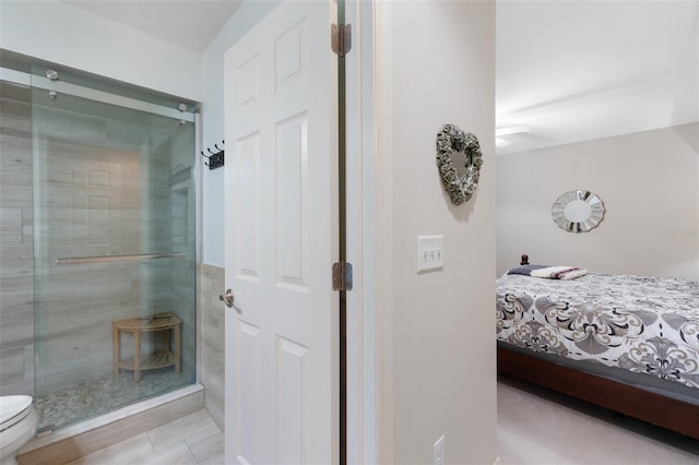 bathroom with toilet and a shower with door