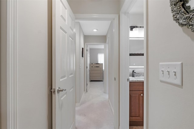 corridor featuring sink and light colored carpet