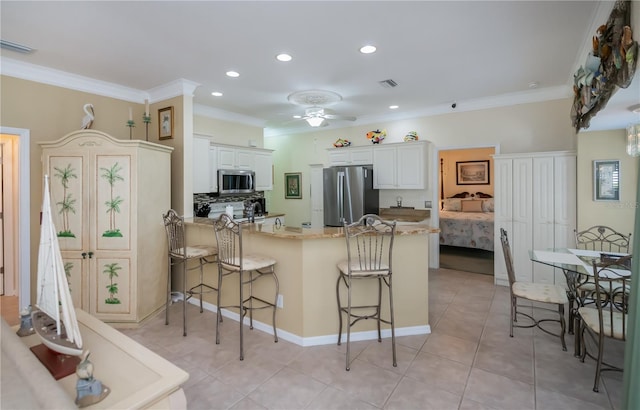 kitchen featuring a breakfast bar, white cabinetry, crown molding, appliances with stainless steel finishes, and kitchen peninsula