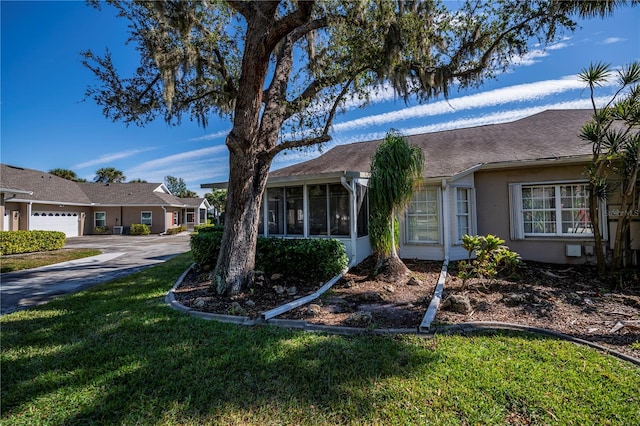 ranch-style house with a sunroom, a front lawn, and a garage