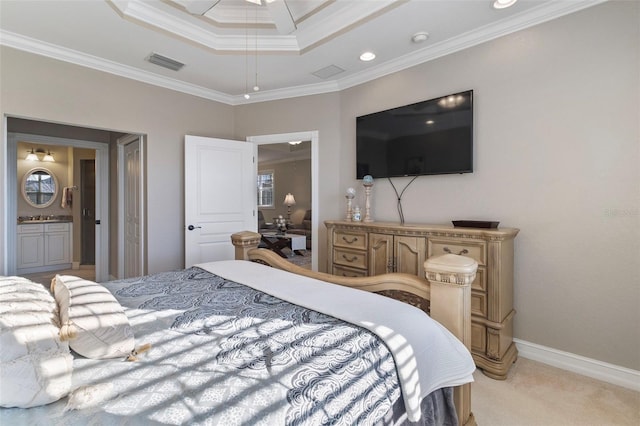 carpeted bedroom with connected bathroom, a tray ceiling, and ornamental molding