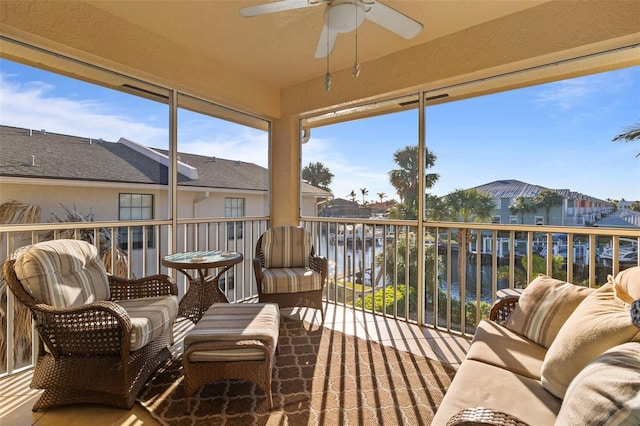 sunroom with ceiling fan and a water view